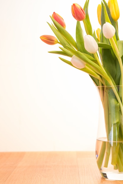 Florero de tulipanes en mesa de madera