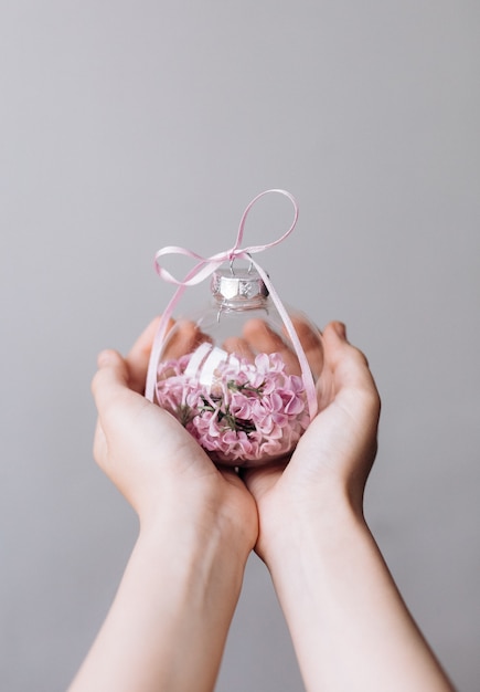 Florero de vidrio con flores lilas centro de manos