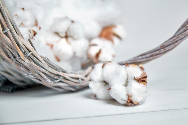 Flores de algodón y una canasta en una mesa blanca de madera