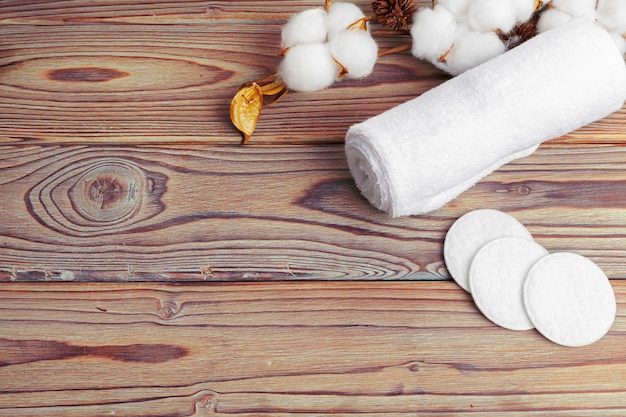 Flores de algodón con toalla en mesa de madera