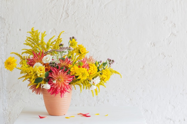 Flores amarelas e vermelhas em um vaso na prateleira vintage