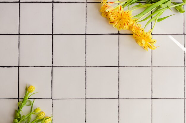 Flores amarillas sobre un fondo de piso de baldosas blancas