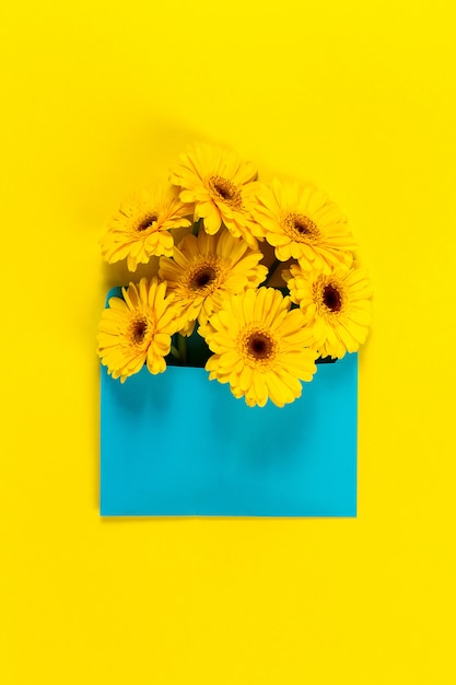 Flores amarillas sobre una mesa amarilla con una tarjeta azul