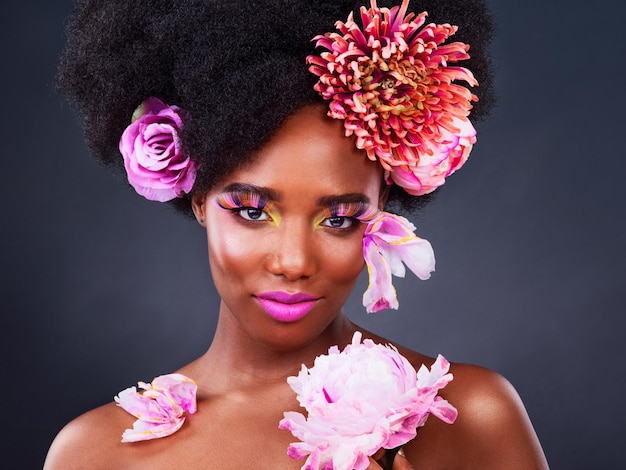 Foto flores de belleza y retrato de mujer negra en estudio para maquillaje creativo y primavera cosmética natural y floral con cara de modelo aislado en el fondo para arte amor propio o confianza