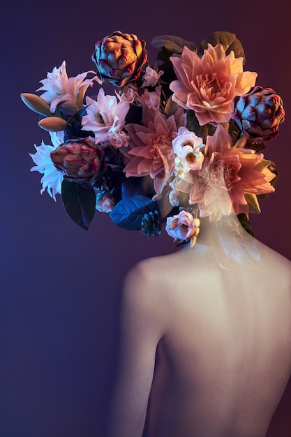 Flores de belleza rostro de mujer con doble exposición. Retrato de una niña de color y luz de neón, maquillaje profesional, espalda desnuda de una mujer, flores en la cabeza