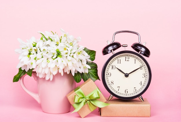 Flores blancas, caja de regalo y despertador.