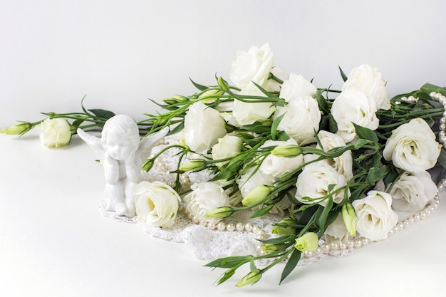 Flores blancas con perlas y un ángel de cerámica.