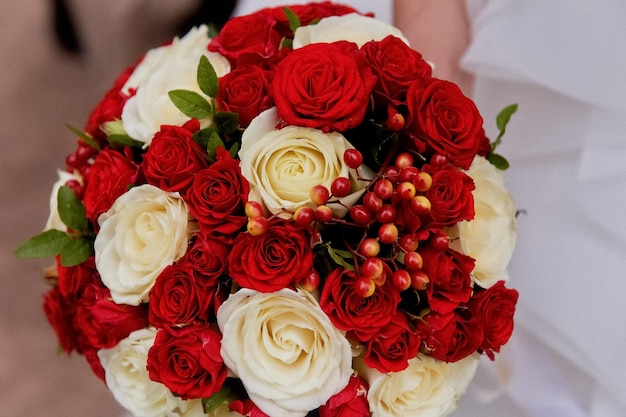 Flores de boda un ramo de rosas rojas y crema con bayas rojasEl ramo de la novia