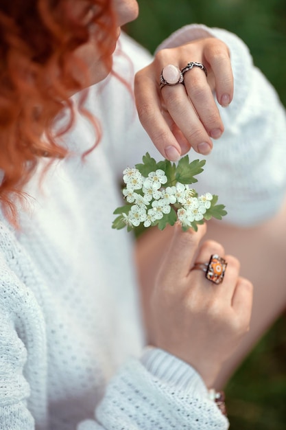 Flores brancas nas mãos de uma garota ruiva