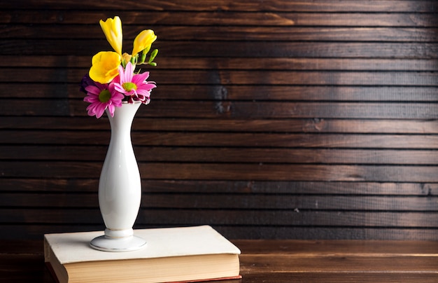 Flores brilhantes em vaso no livro