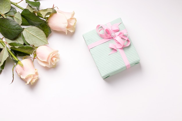 Flores y caja de regalo sobre fondo rosa