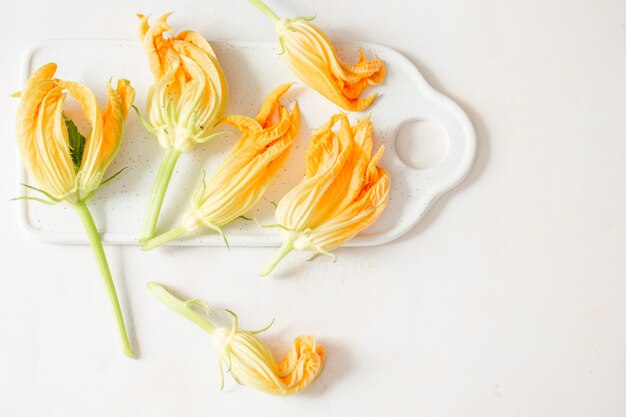 Flores de calabacín en un tablero blanco