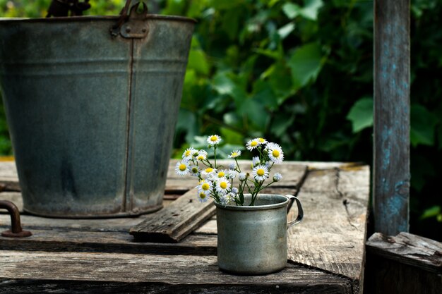 Flores de campo en una vieja taza vintage en la naturaleza