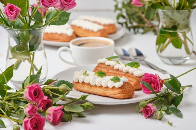 Flores y canutillos decorados con crema y menta sobre una mesa blanca. Postre para una cita romántica. Tortas para las vacaciones.