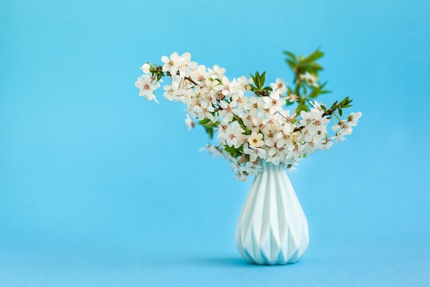 Flores de cerezo en florero azul sobre azul