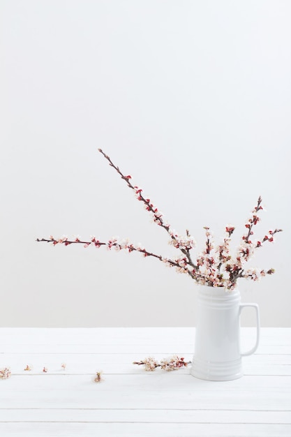 Flores de cerezo en florero sobre fondo blanco.