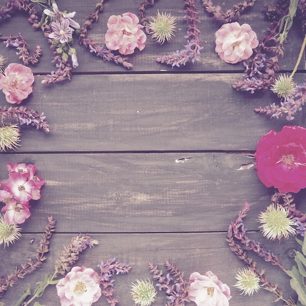 Flores en un círculo en una postal de fondo de madera para las vacaciones rosas geranios lavanda salvia un