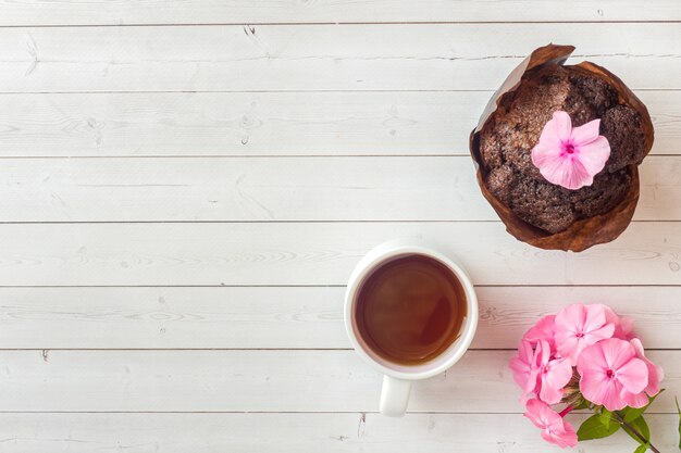 Flores cor-de-rosa do flox e uma xícara de café em uma tabela branca.