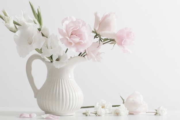 Flores cor de rosa e brancas em um vaso na mesa branca