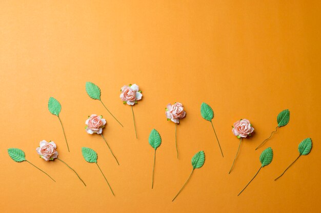 Flores cor de rosa e folhas verdes sobre fundo laranja.