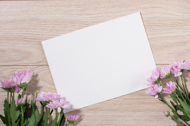 Foto flores cor de rosa e papel vazio para o seu texto em fundo de madeira