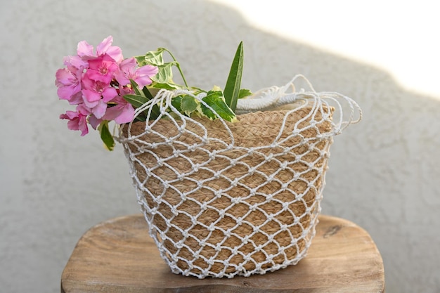 Flores cor de rosa rododendro em uma cesta de palhas trançadas em um fundo texturizado branco