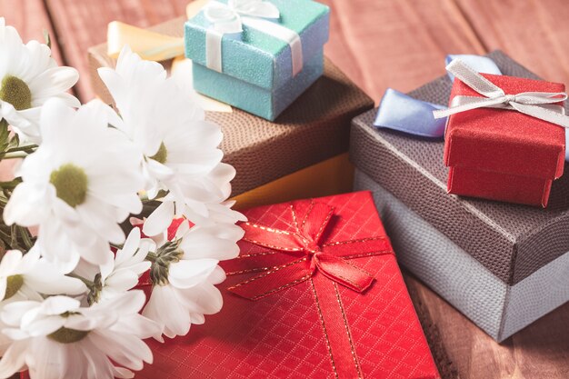 Flores de crisantemo blanco con cajas de regalo en mesa de madera