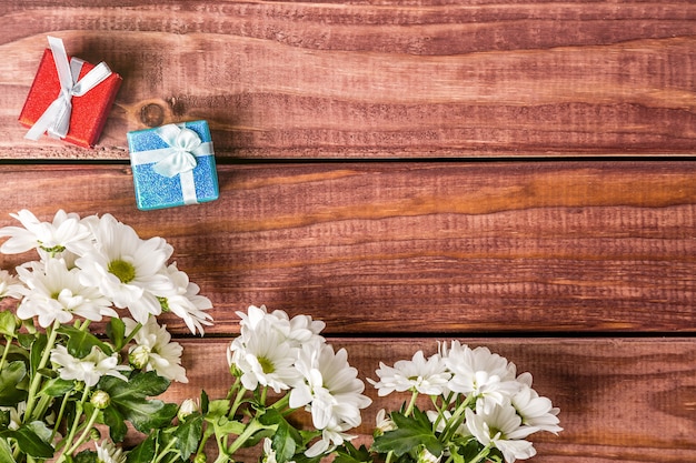 Flores de crisantemo blanco con cajas de regalo sobre fondo de madera