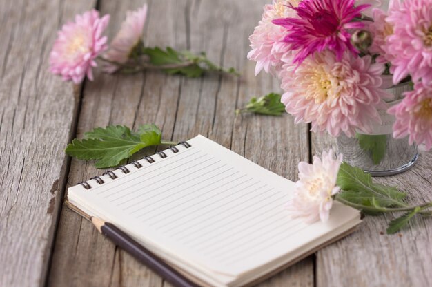 flores con cuaderno en mesa de madera