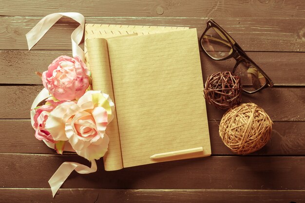 Flores y un cuaderno en la mesa de madera