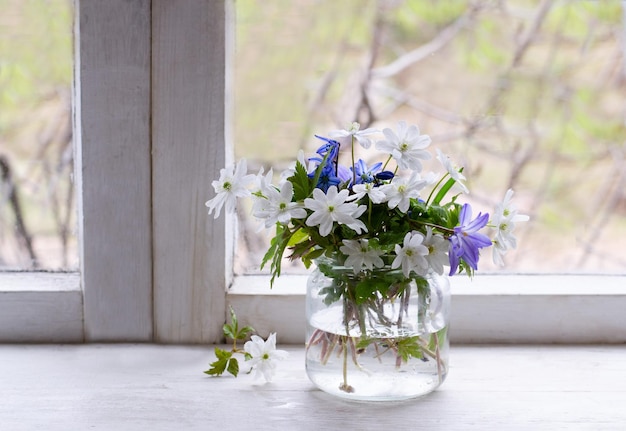 Flores da primavera em frasco de vidro no peitoril da janela