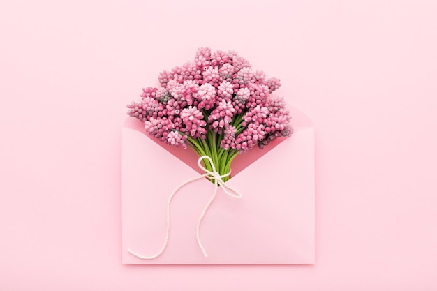 Flores da primavera em um envelope rosa para a postura plana do dia das mães