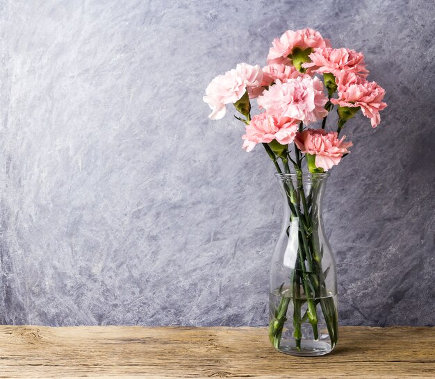 Flores de cravo-de-rosa em garrafa transparente com espaço de cópia