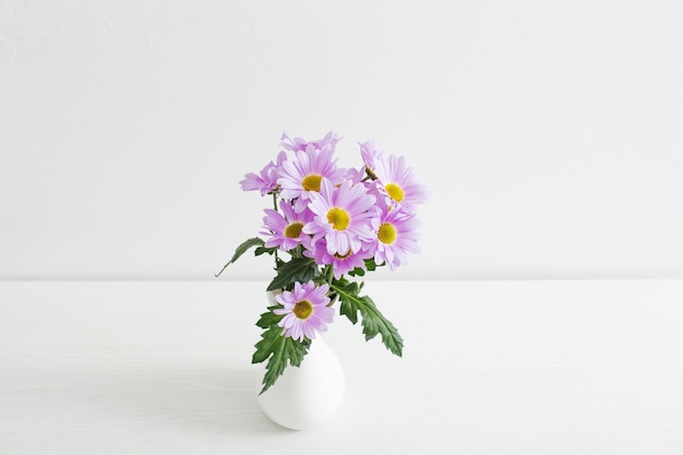 Flores de crisântemos em vaso de cerâmica no fundo branco