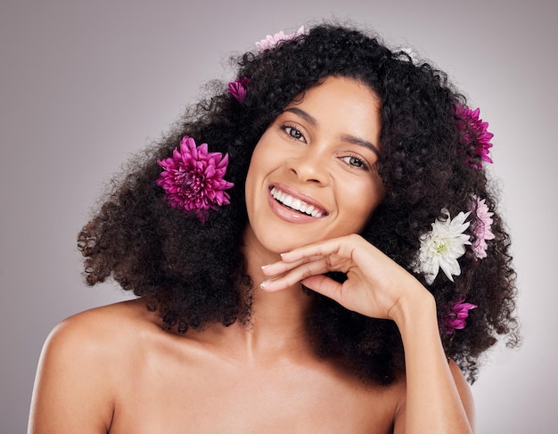 Flores de cuidado de cabelo de retrato de rosto e mulher negra em estúdio isolado em fundo cinza Cosméticos florais maquiagem orgânica e modelo feminino feliz com flor para penteado beleza cuidados com a pele ou bem-estar