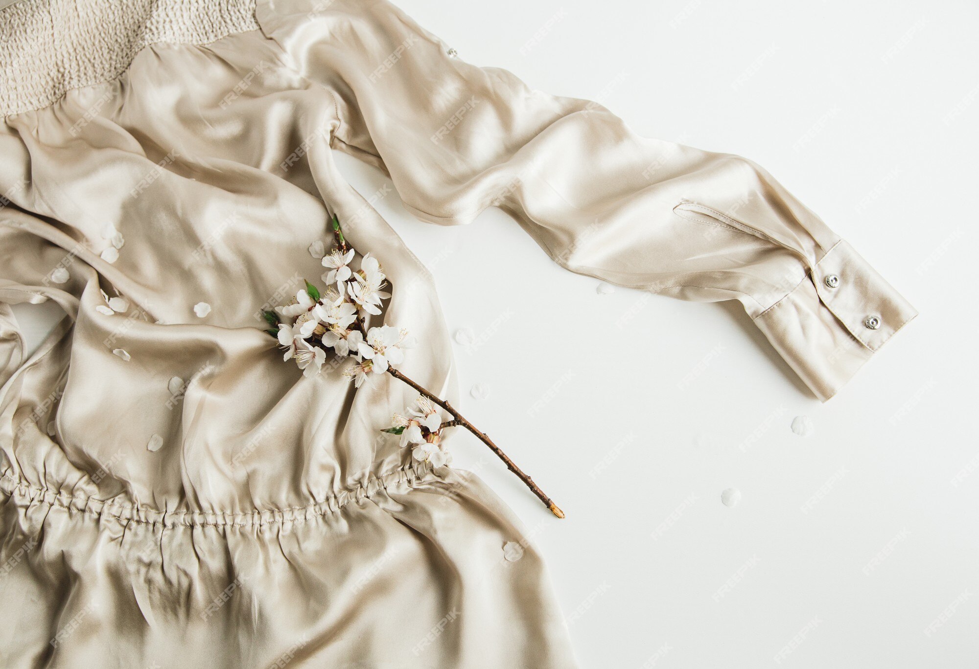 Flores de flor branca em roupas de tecido de seda bege em fundo branco |  Foto Premium