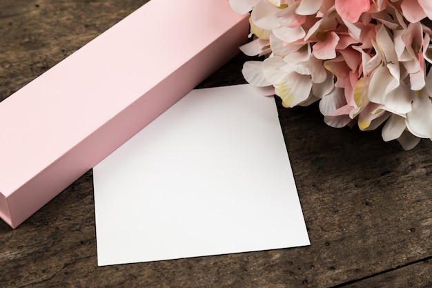 Flores de hortênsia rosa pastel, caixa de presente e um pedaço de papel em uma madeira. copyspace para texto