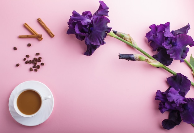 Flores de íris roxas e uma xícara de café em rosa pastel