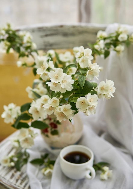 Flores de jasmim em um vaso branco. Stillife com jasmim e café.