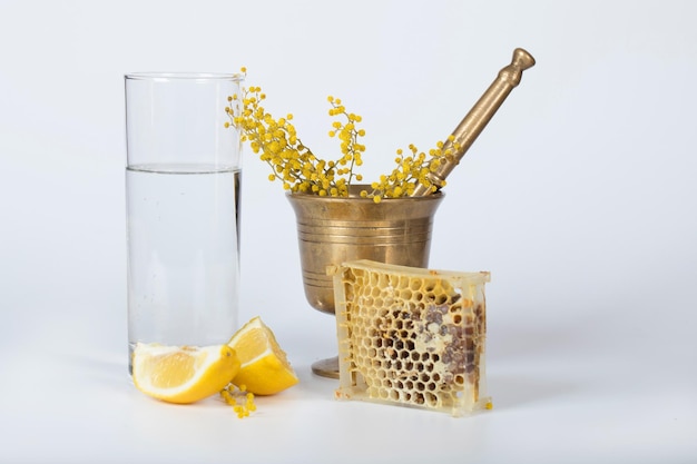 Flores de mimosa em uma argamassa de bronze em uma superfície de plástico cinza. Fechar-se