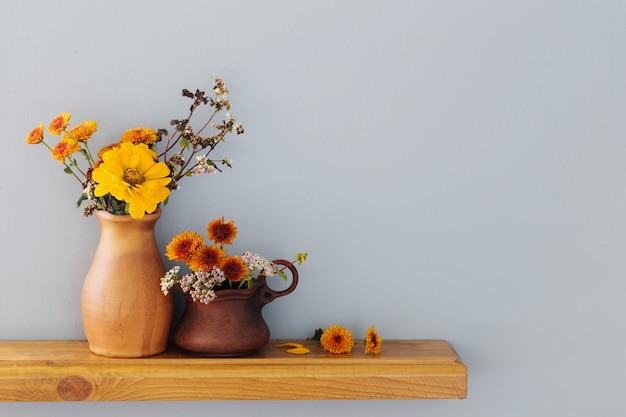 Flores de outono em vaso de cerâmica rústico na parede cinza do fundo