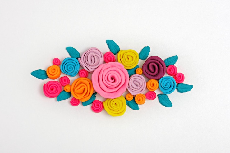 Foto flores de plasticina multicoloridas compõem rosas brilhantes em fundo branco