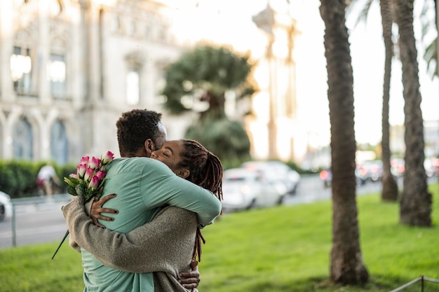 Flores de presente de dia dos namorados de casal afro-americano se abraçam alegremente