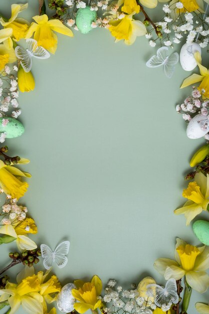 Flores de primavera e ovos de Páscoa em fundo verde com espaço para cópia