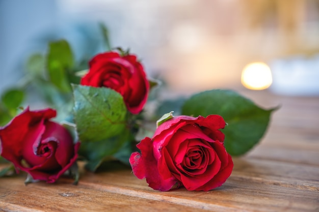 Flores de rosas vermelhas na mesa de madeira com desfoque de fundo