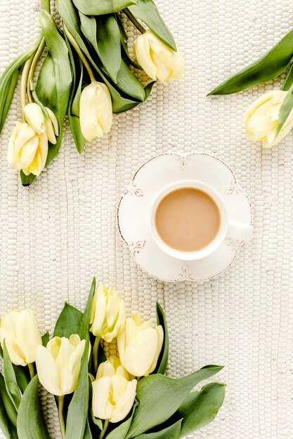 Flores de tulipa amarela e xícara de café plana vista superior