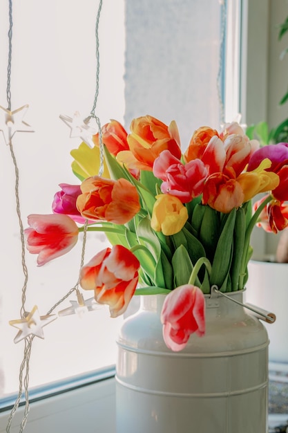 Flores de tulipas coloridas brilhantes em um vaso na janela Foto de alta qualidade