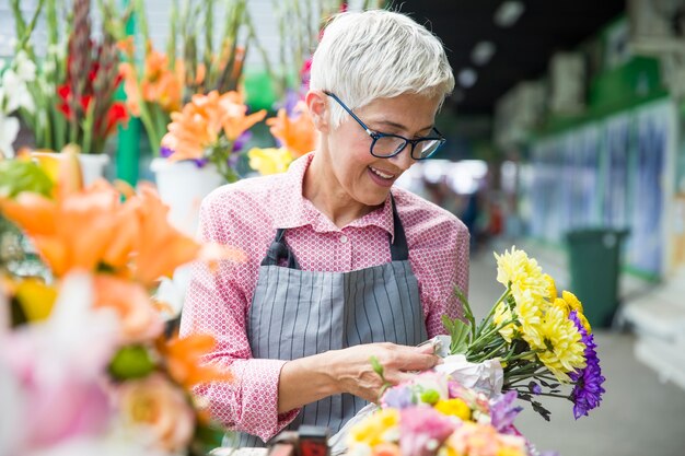 Flores de vendas mulher sênior no mercado de flores locais