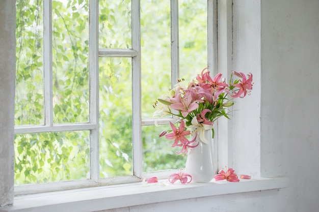 Flores de verão em um vaso no parapeito da janela branca