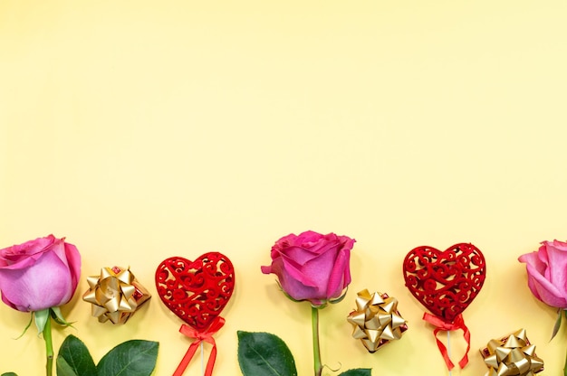 Flores y decoración en forma de corazones estampados sobre un fondo amarillo Rosas y gerberas en amarillo Día de San Valentín Composición fácil Lugar para texto Cajas de regalo